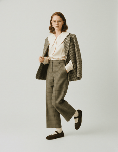 Woman wearing a checkered suit and Prada Coffee Collapse Re-Nylon and Suede Ballerinas 1F215O_D7C_F0201_F_005 with a white shirt on a plain background