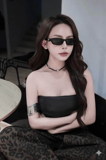 Woman wearing a black dress and Prada PR B06S 16K08Z Square Symbole Sunglasses indoors