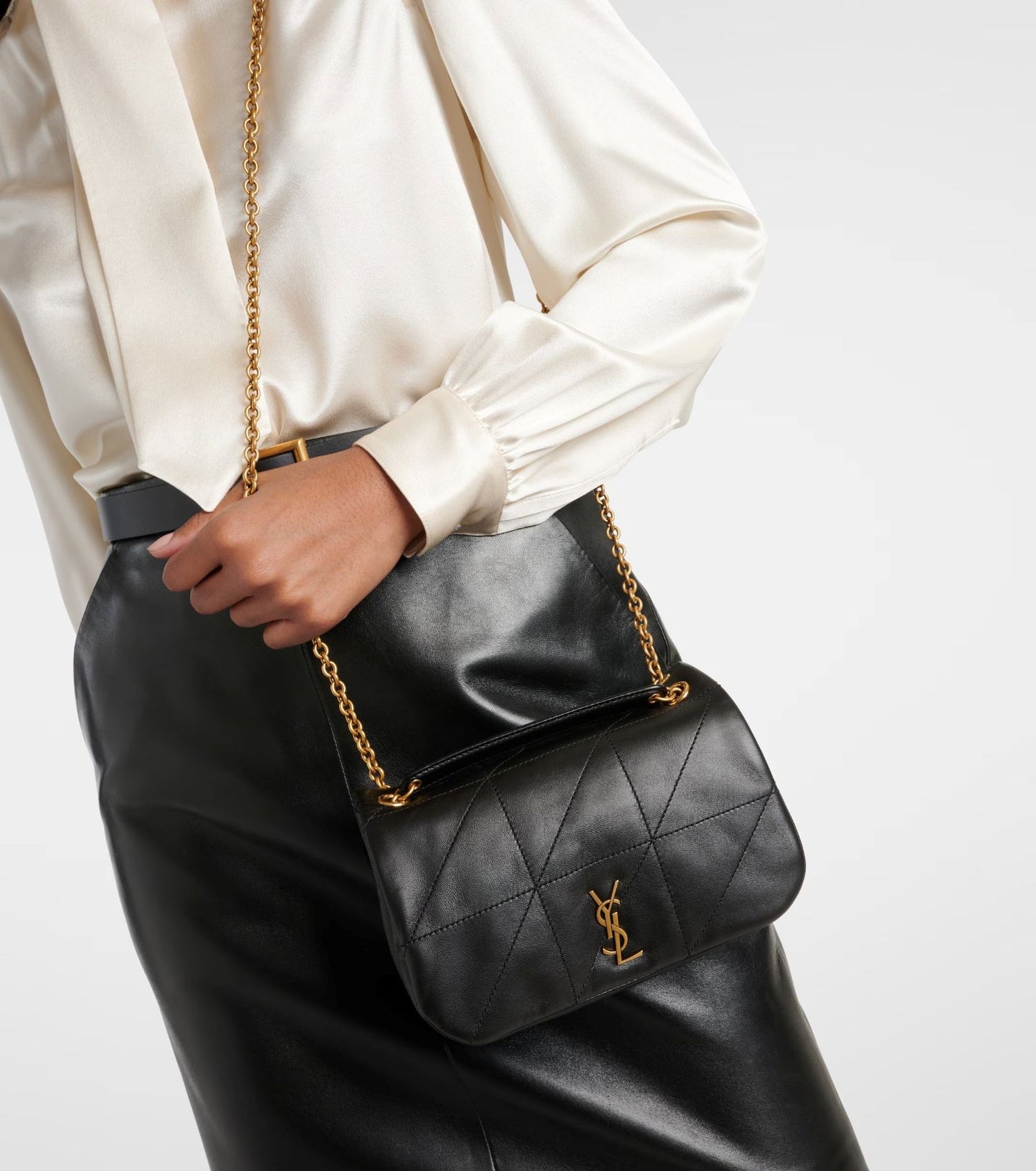 Person holding a Saint Laurent JAMIE 4.3 Mini in Lambskin – Noir 766754AAB321000 with gold chain strap on a white background
