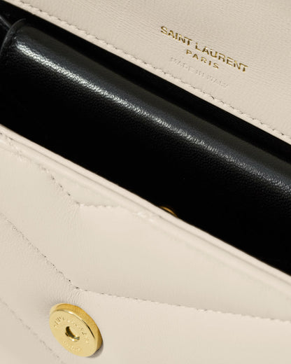 Close-up of a Saint Laurent handbag with gold logo and black interior.