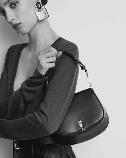Person holding a Saint Laurent Mini Voltaire Top Handle Bag in Box 8008460SX0W1000 with a visible brand logo against a plain background