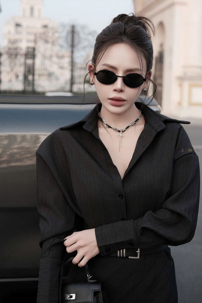 Woman wearing a black outfit with Saint Laurent SL 692 001 Oval Sunglasses in an urban setting