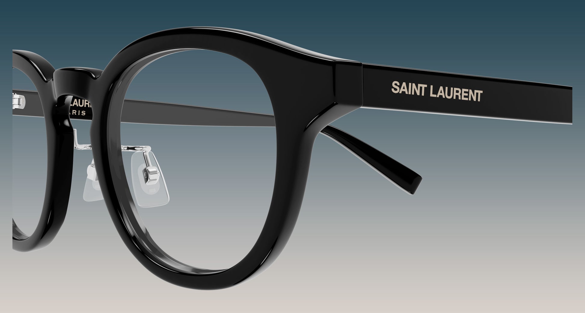 SL 907/F 001 Black Round Eyeglasses with clear lenses, featuring the brand name 'SAINT LAURENT' printed in gold on the temple arm, set against a gradient gray background.