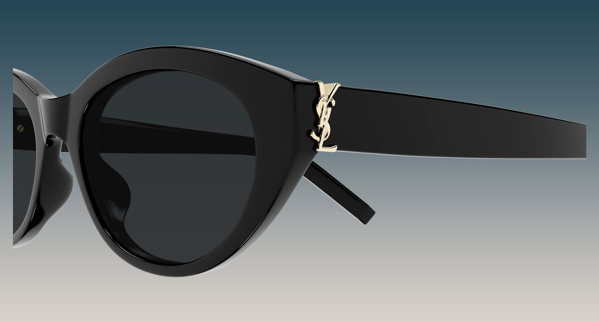 Saint Laurent SL M148 001 Black Round Sunglasses with dark lenses and a gold-tone YSL logo on the temple, shown against a gradient blue-to-gray background.