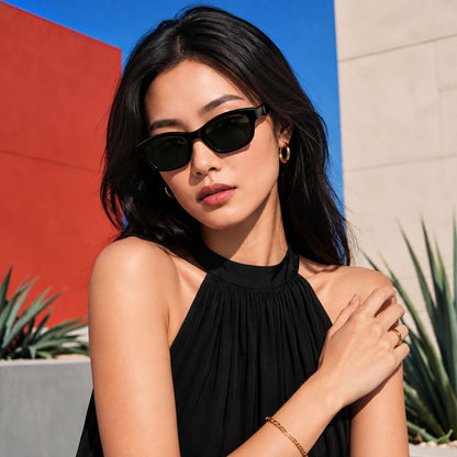 A woman wearing Saint Laurent SL M172 001 Black Rectangular Sunglasses and a black halter top, posing outdoors against a colorful background of red, blue, and beige walls with plants.