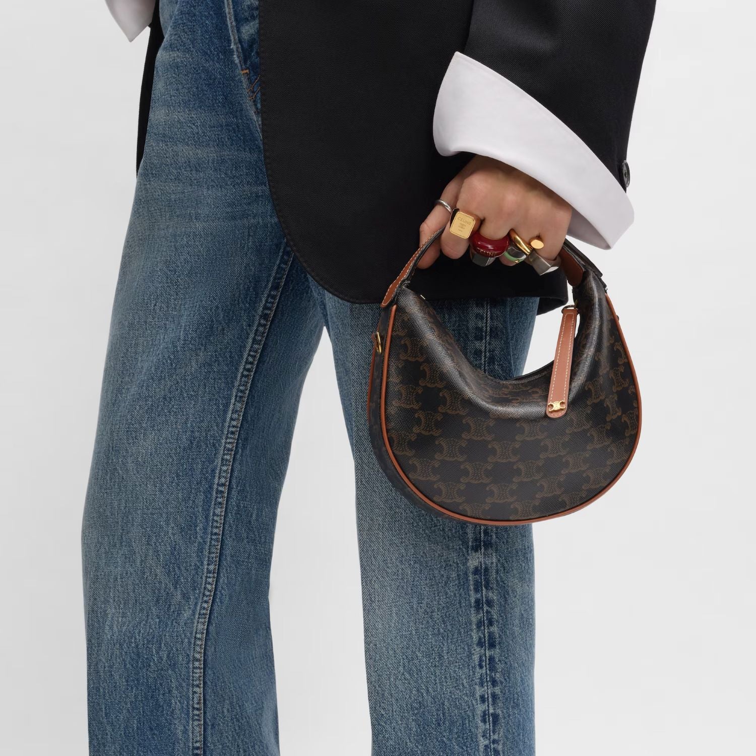 person wearing blue jeans and black suit with Teen Celine Lulu in Triomphe Canvas and Calfskin Tan 120722FQM.04LU on white background