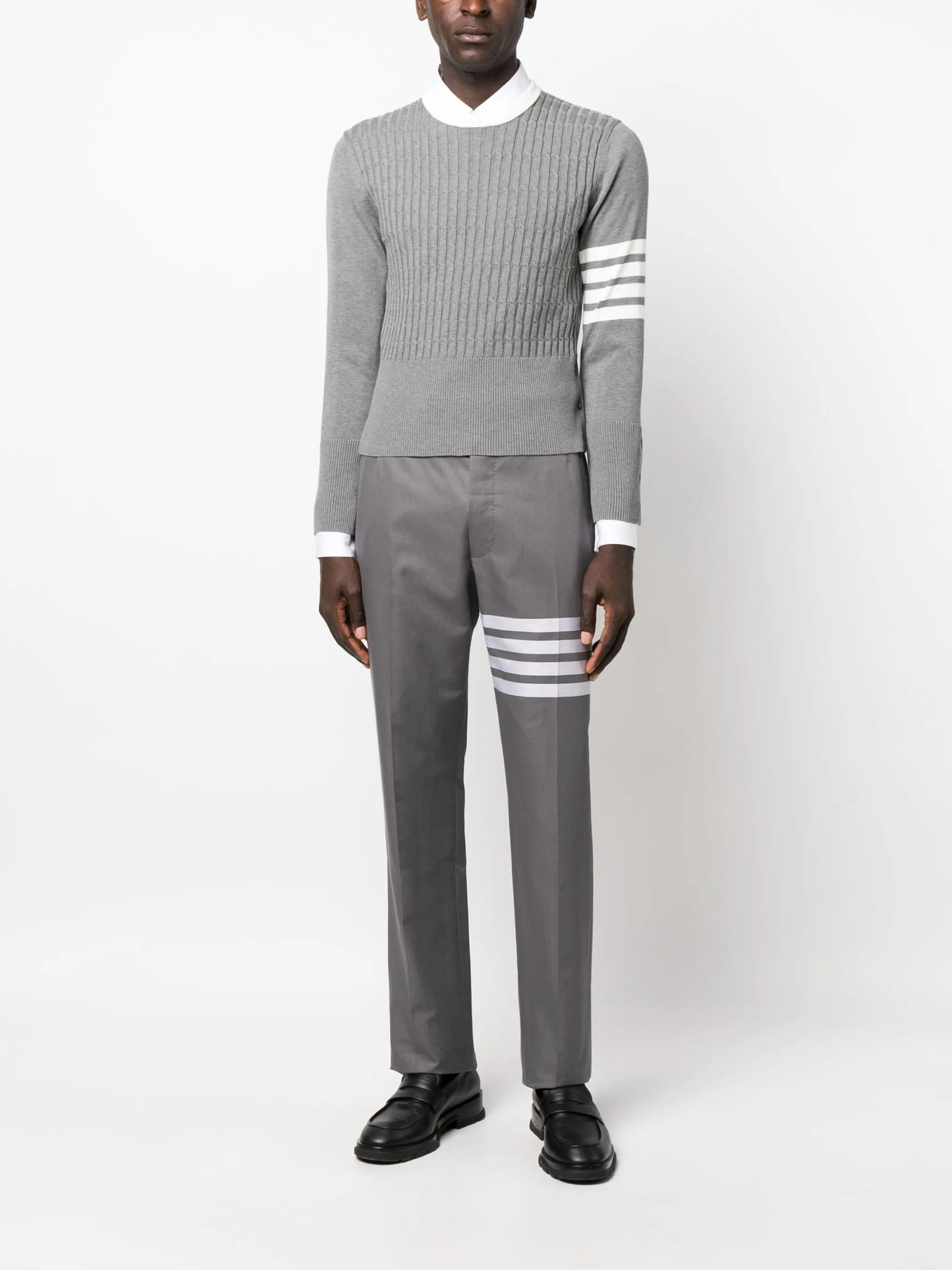 Person wearing aThom Browne 4-Bar Placed Baby Cable Sweatshirt MKA497A Y3014 055 and pants with white stripes on a white background