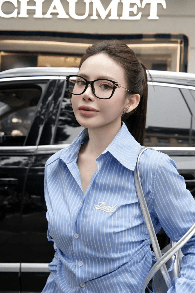 Woman wearing Tiffany & Co TF2266 8001 Eyeglasses in a blue striped shirt with a silver bag in front of a black car, with 'CHAUMET' branding.