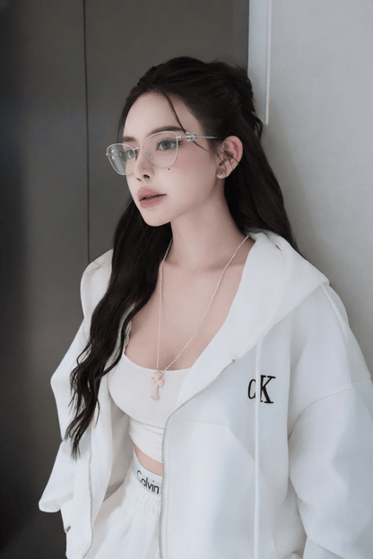 Woman wearing a Tiffany TF1166 6001 Silver Eyeglasses & a white jacket with a brand logo, standing against a neutral wall.