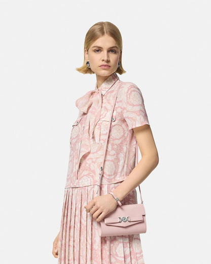 Woman wearing a pink floral outfit with a Versace Medusa '95 Crossbody Bag Light Pink 1014319 1A10795 1PT2P on a white background