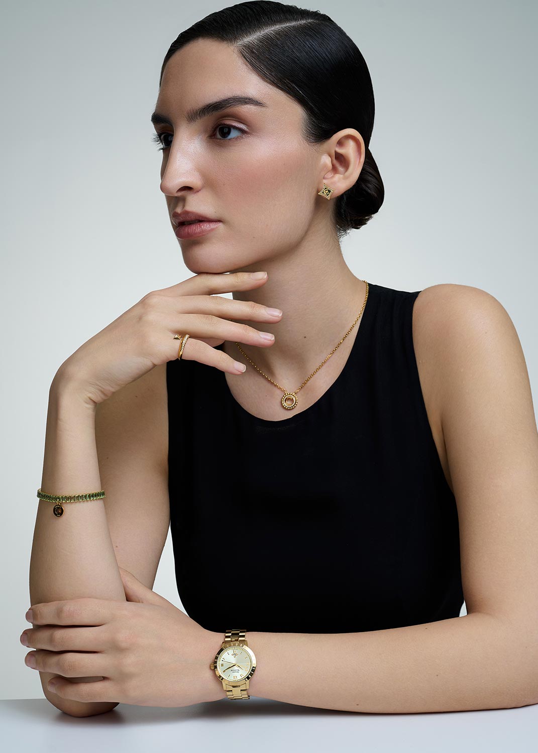 Woman wearing gold jewelry including a necklace, bracelet, and Vivienne Westwood Bloomsbury Gold Watch vv152gdgd on a plain background