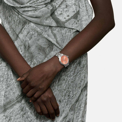 Person wearing a Vivienne Westwood Dulwich Pink Dial Silver Watch vv307cosl with a stone-patterned background