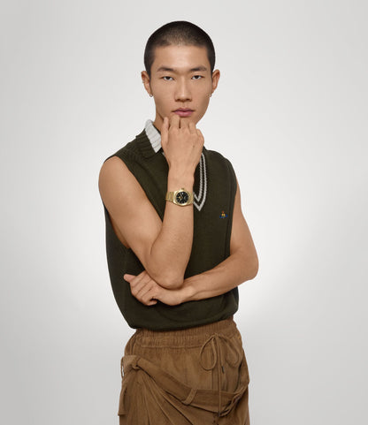 Man wearing a green sleeveless sweater and Vivienne Westwood Hanwell Black Dial Gold Watch VV335BKGD 8050164231910 on a white background
