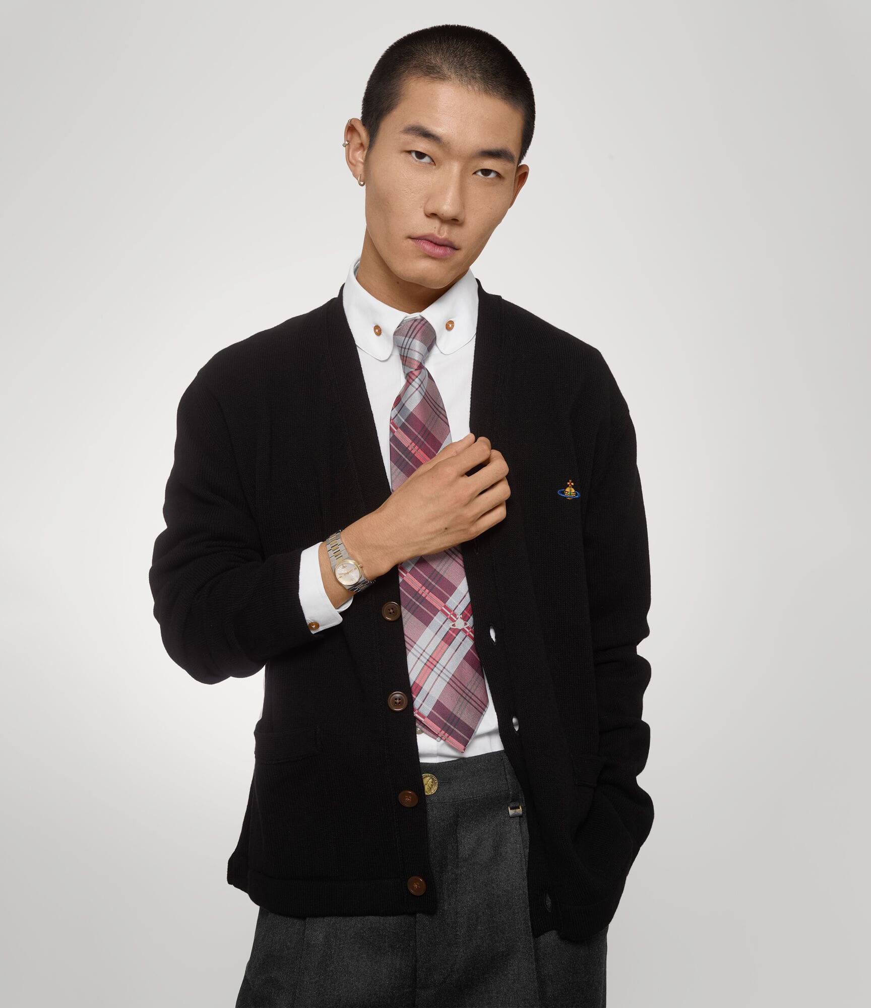 Man wearing a black cardigan over a white shirt with a Vivienne Westwood Hoxton Dual-Tone Silver Watch VV332SLSG 8050164231880 on a light gray background