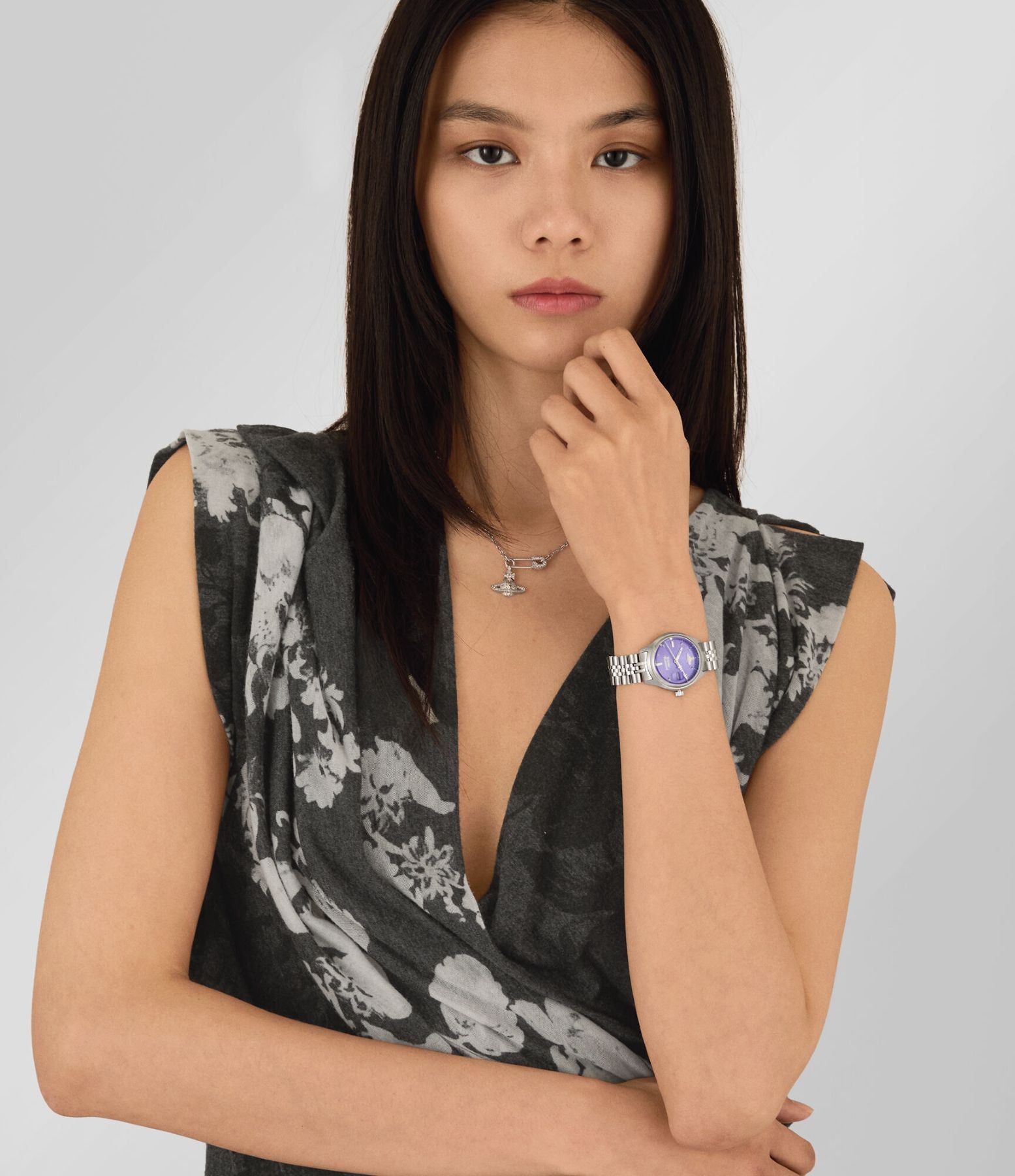 Woman wearing a floral top and a Vivienne Westwood Little Camberwell Purple Dial Silver Watch vv311ppsl with a purple gemstone on a plain background
