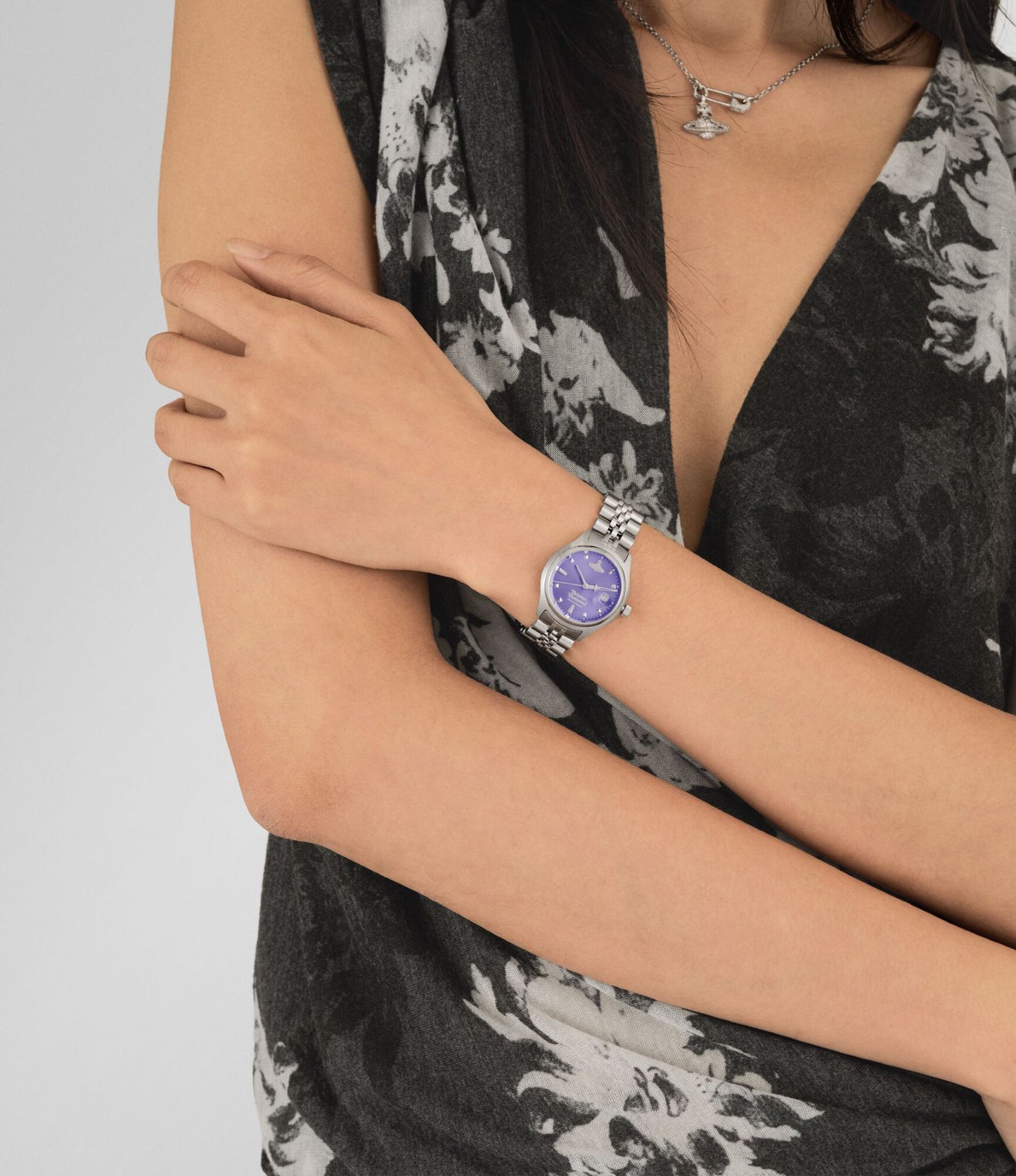 Women wearing a Vivienne Westwood Little Camberwell Watch vv311ppslwith a purple face and silver band, dressed in a black floral outfit.