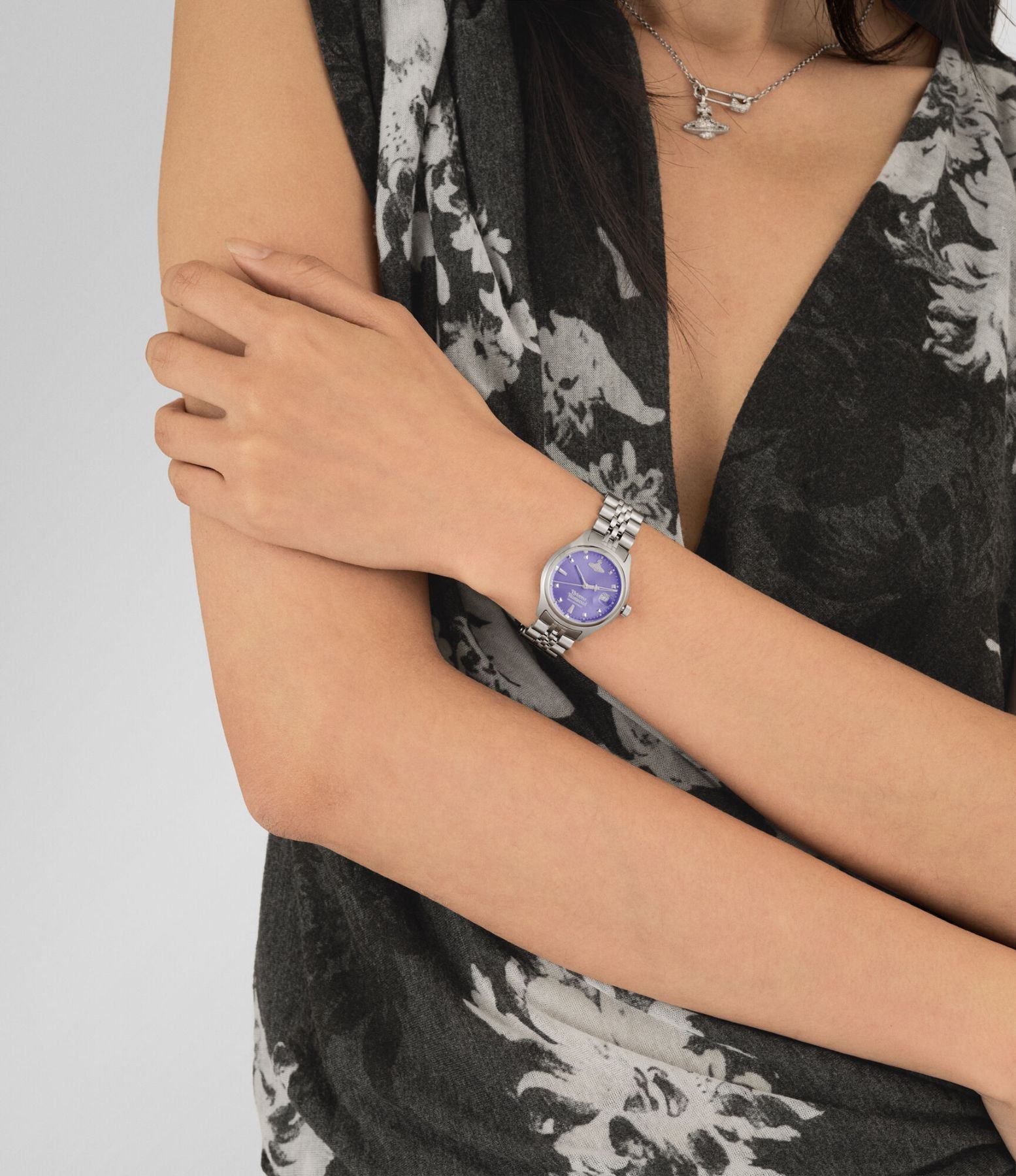 Women wearing a Vivienne Westwood Little Camberwell Watch vv311ppslwith a purple face and silver band, dressed in a black floral outfit.