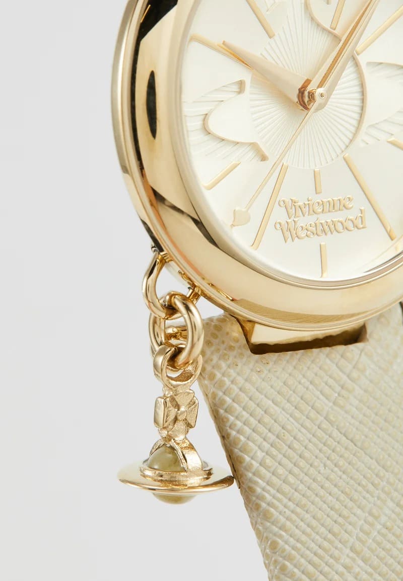 Close-up of a Vivienne Westwood Orb Pop Champagne Gold Ladies Watch vv006gdcm with a textured cream dial and a matching cream textured strap, featuring a dangling gold bell charm.