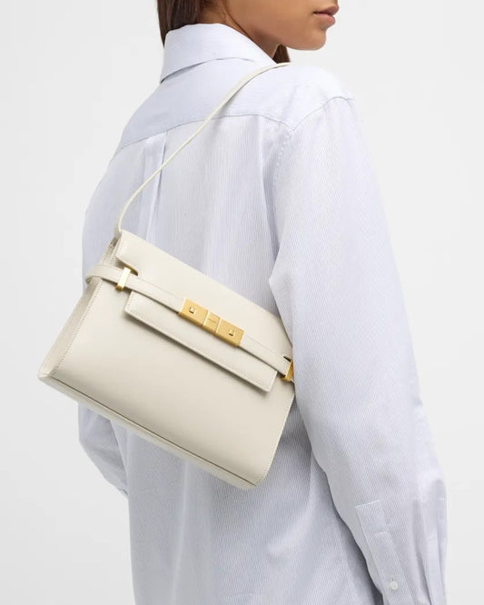 Person wearing a white shirt with a YSL Mini Manhattan In Box Saint Laurent Blanc 7277660SX0W9207 featuring gold hardware.