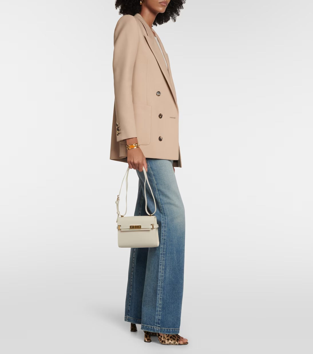 Woman holding a YSL Mini Manhattan In Box Saint Laurent Blanc 7277660SX0W9207 wearing a beige blazer and blue jeans on a white background